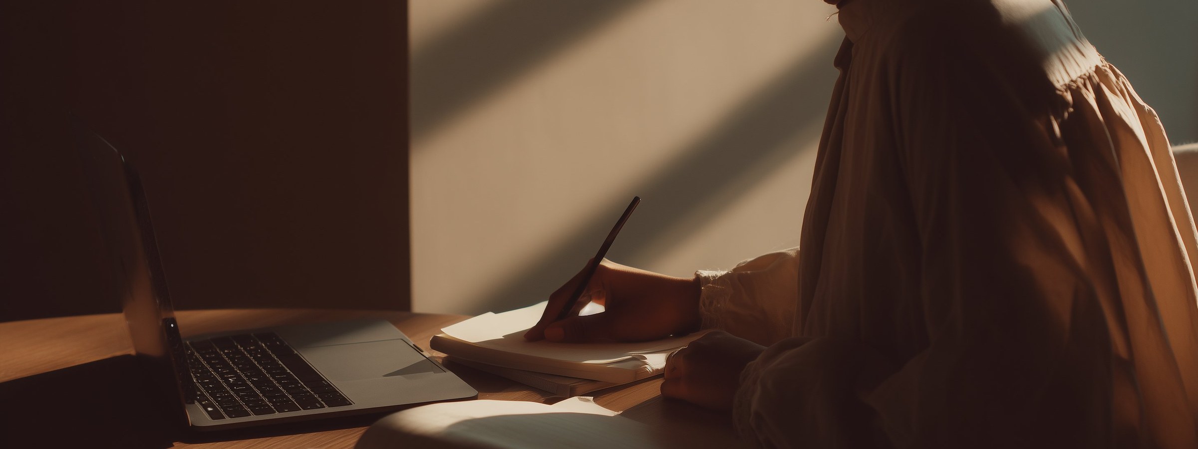 A focused learner with a notebook and laptop, attending an online masterclass